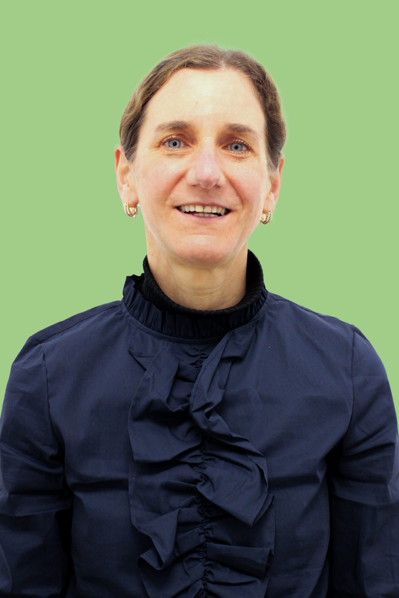 Ein Portrait-Foto von Christine Krause-Tiedtke, Therapeutin für Sprachtherapie. Sie trägt ein dunkel blaues Hemd, hat zusammengebundene braune Haare und lächelt in die Kamera.