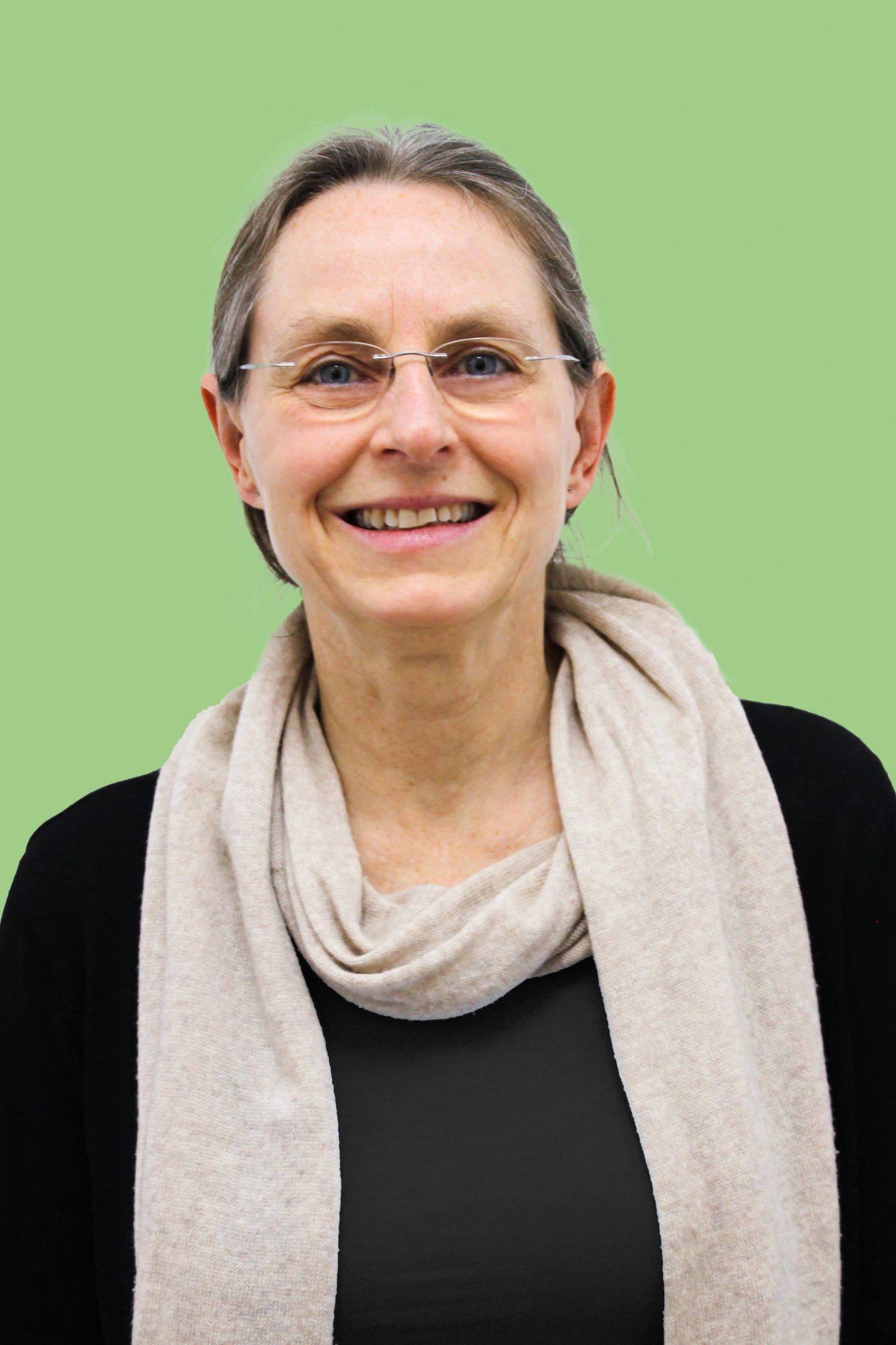 Ein Portrait-Foto von Michaela Malchin, Therapeutin für Sprachtherapie. Sie hat mittellange dunkelblonde Haare, trägt eine Brille und schaut lächelnd in die Kamera. Der Hintergrund ist grün gefärbt.